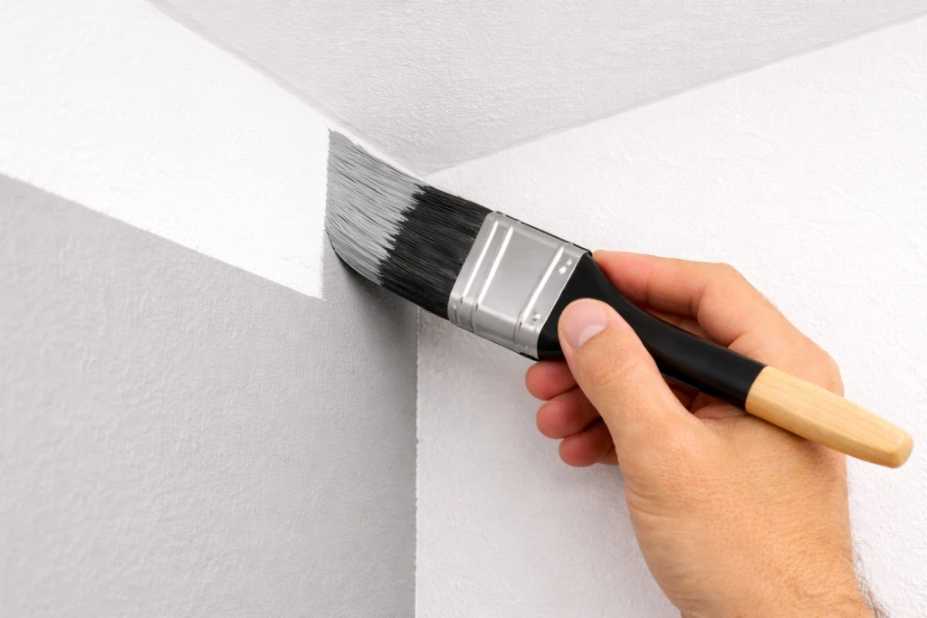 Paintbrush cutting in corner where two walls meet showing proper technique
