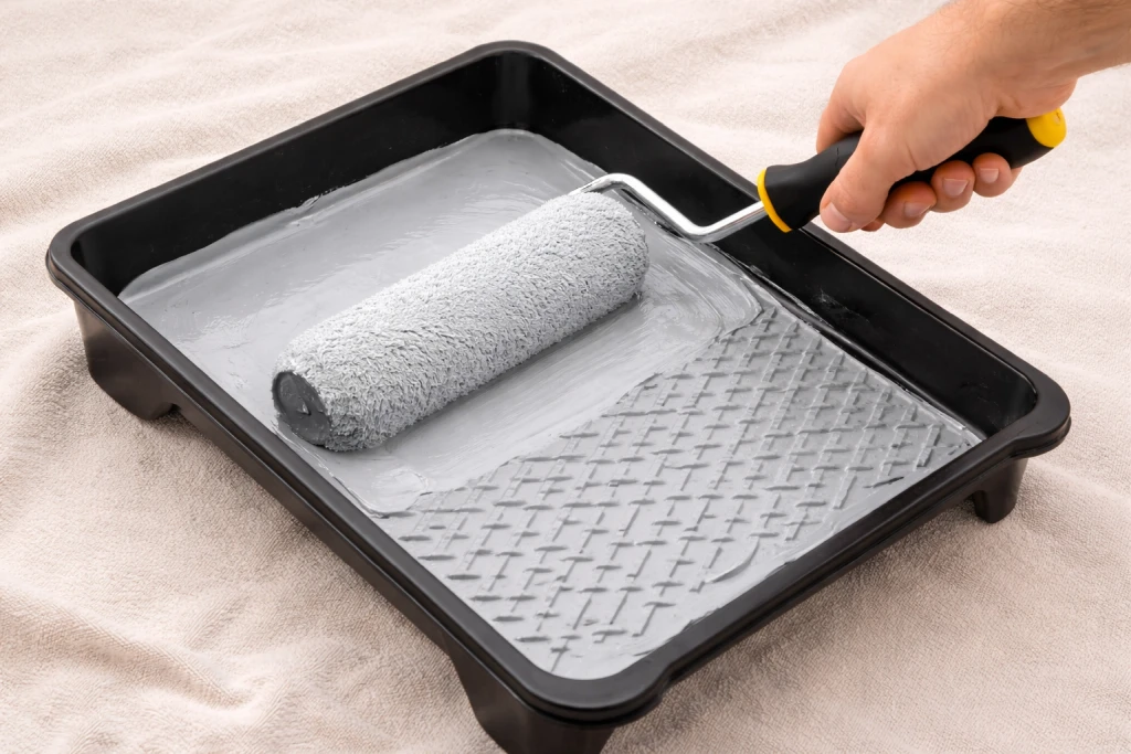 Paint roller being loaded in tray showing correct amount of paint coverage on roller sleeve
